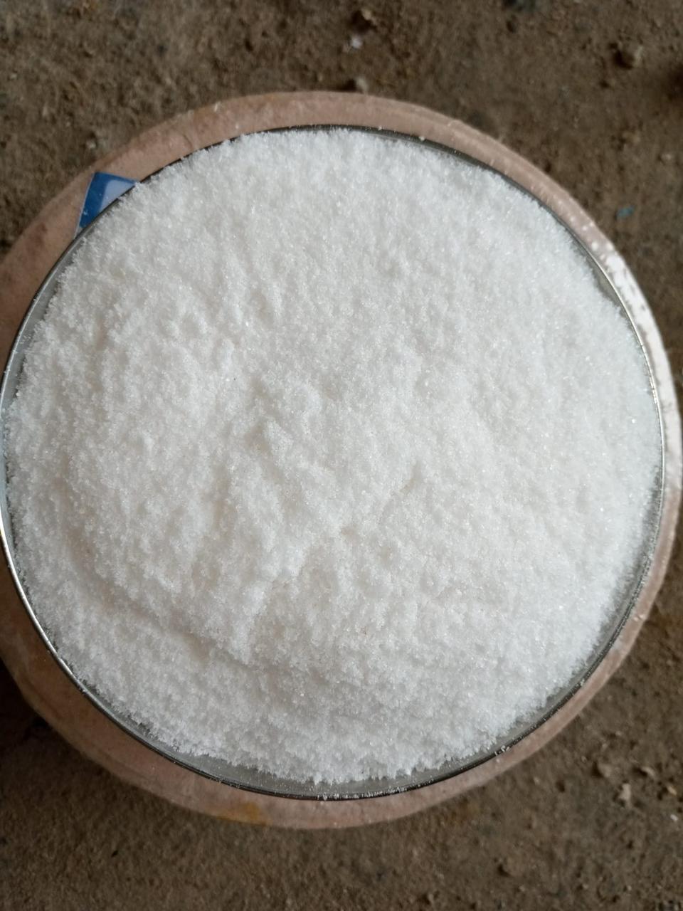 Top-down view of fine white refined salt filling a round metal testing pan in a quality control setting
