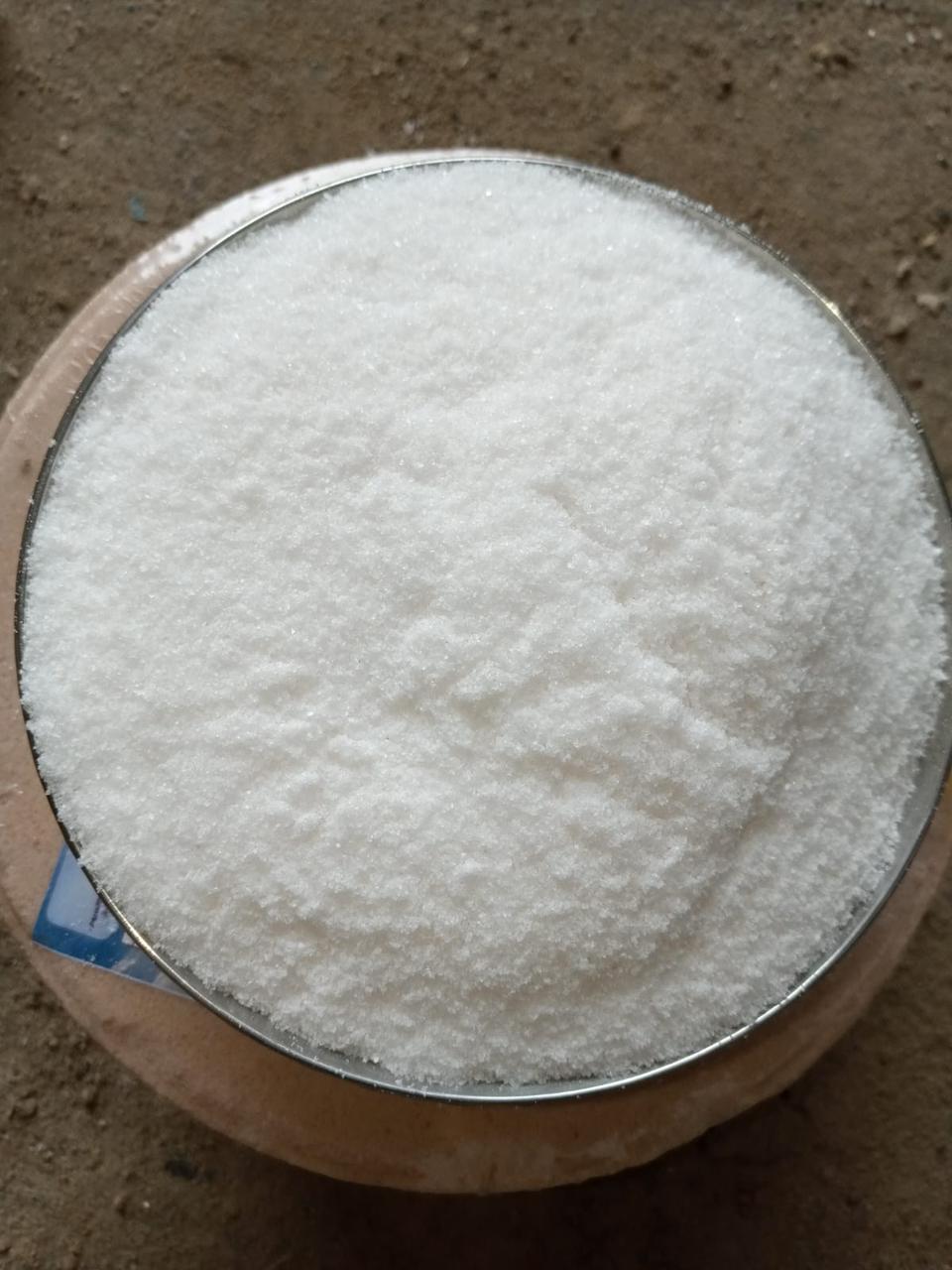 Top-down view of a round container filled with fine bright white processed salt in a testing environment